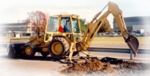 A yellow excavator digging a hole